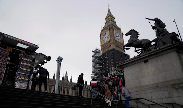 Tourists visit memorabilia stalls in the shadow of the Queen Elizabeth II tower that contains the bell known as 'Big Ben' in London, Tuesday, Jan. 18, 2022 (AP Photo/Alastair Grant)