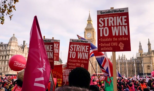 Royal Mail workers hold placards and banners as they gather in Parliament Square, to hold a protest over pay and jobs. (AP)