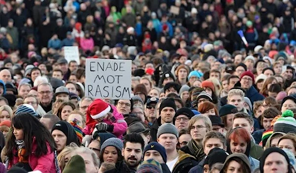 People demonstrating against nazism and racism hold a placard reading “united against racism” in Kärrtorp, a suburb of Stockholm. (AFP)