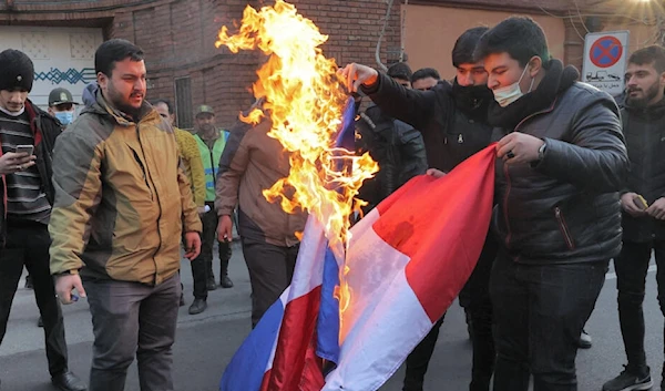 Demonstrators burn a French flag during a protest against Charlie Hebdo, in front of the French embassy in Tehran, Iran, on January 8, 2023 (AFP).