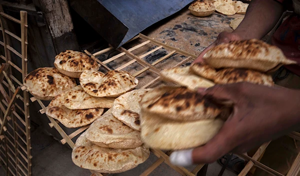 worker collects Egyptian traditional 'baladi' flatbread, at a bakery, in el-Sharabia, Shubra district, Cairo, Egypt, Wednesday, March 2, 2022 (AP Photo/Nariman El-Mofty, File)