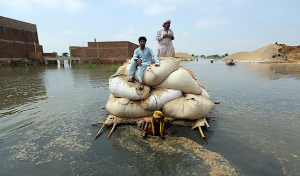 Flood victims from monsoon rain use a makeshift barge to carry hay for cattle, in Jaffarabad, a district of Pakistan's southwestern Baluchistan province, on Sept. 5, 2022 (AP Photo/Fareed Khan)