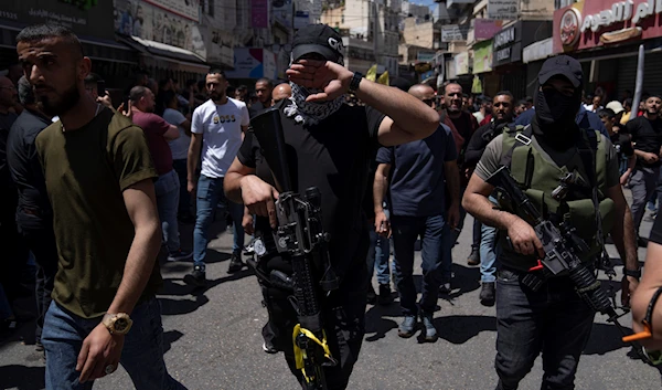 A Palestinian fighter from the Lions' Den group covers his face at the sight of a camera in the West Bank city of Nablus, occupied Palestine, May 4, 2023 (AP)