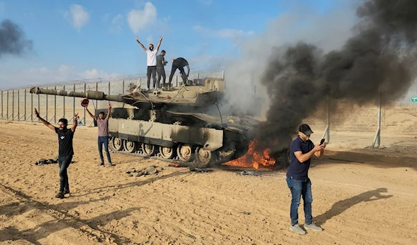 Palestinians celebrate by a destroyed Israeli tank at the Gaza Strip fence east of Khan Younis Saturday, Oct. 7, 2023 (AP Photo/Hassan Eslaiah, File )