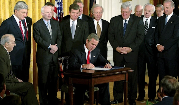 President George W. Bush signs a resolution authorizing the use of force against Iraq, October 16, 2002, in the East Room of the White House (AP)