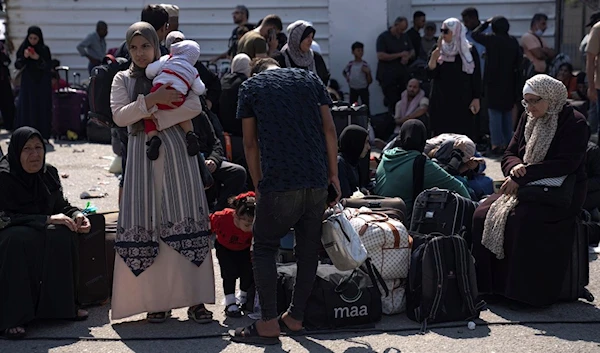 Palestinians wait to cross into Egypt at the Rafah border crossing in the Gaza Strip, occupied Palestine, October 16, 2023 (AP)