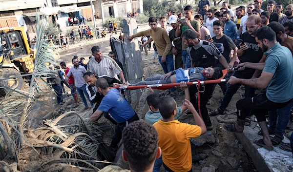 Palestinians carry a person wounded in Israeli airstrikes in Khan Yunis, Gaza Strip, occupied Palestine, October 16, 2023 (AP)