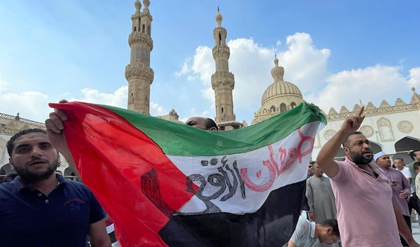 Protesters hold a Palestinian flag reading 'Al-Aqsa flood in Arabic, as they leave Friday prayers at al-Azhar mosque, the Sunni Muslim world's premier Islamic institution, in Cairo, Egypt, Friday, Oct. 13, 2023. (AP)