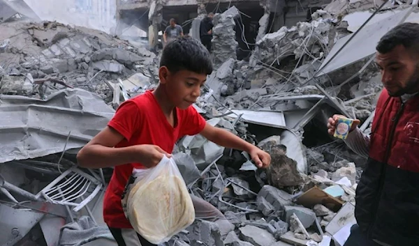 A Palestinian youth carries bread amid the rubble of the city center of Khan Yunis in the southern Gaza Strip following Israeli shelling on October 10. (AFP via Getty Images)