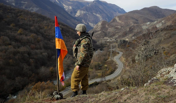 An Armenian soldier stands guard next to Nagorno-Karabakh's flag atop the hill near Charektar in the region of Nagorno-Karabakh, Nov. 25, 2020 (AP)