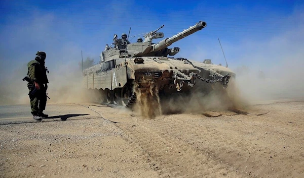 Israeli reserved soldiers direct a Merkava tank to cross a road in the southern Israel as it advances towards Gaza, Friday, Aug. 1, 2014. (AP Photo/Tsafrir Abayov)