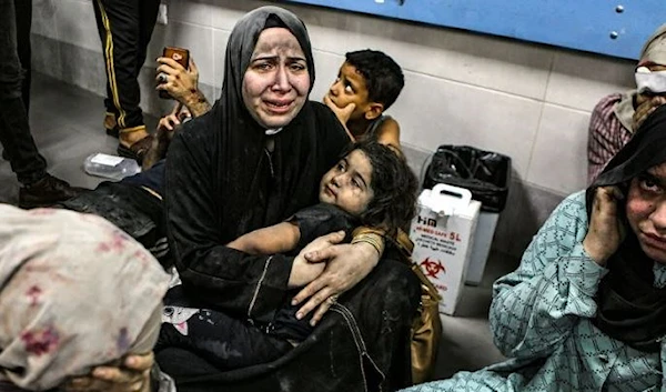 Wounded Palestinian women and children sit on the floor at the Al-Ahli Baptist Hospital following Israeli massacre on Tuesday, October 17. (AP)