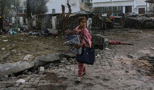 A Palestinian girl carries a blankets as she walks past the site of a deadly Israeli airstrike at Al Ahli hospital, in Gaza City, Oct. 18, 2023. (AP)