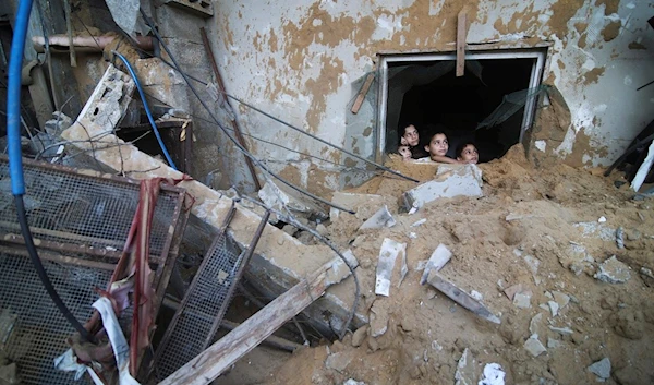 Palestinian children look at a building destroyed in Israeli airstrikes in Rafah, Gaza Strip, occupied Palestine October 14, 2023 (AP)