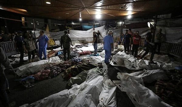 Bodies of Palestinians killed by an explosion near the Ahli Arab hospital are gathered in the front yard of the al-Shifa hospital, in Gaza City, central Gaza Strip, October 17, 2023 (AP)