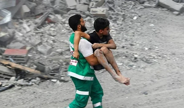 A member of the Palestinian Civil Defence carries a wounded boy rescued from the rubble of a home that was destroyed in an Israeli airstrike on October 9. (AFP via Getty Images)