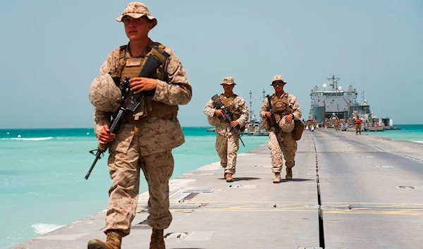 US Marines walk down a removable Trident Pier leading to an American ship docked near an Emirati military base home to a Military Operations and Urban Terrain facility in al-Hamra, United Arab Emirates, Monday, March 23, 2020. (AP)