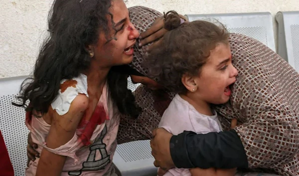 A Palestinian woman comforts her children as they wait at the hospital to be checked due to an Israeli air strike, in the city of Rafah, in the southern Gaza Strip on October 12, 2023. (AFP via Getty Images)