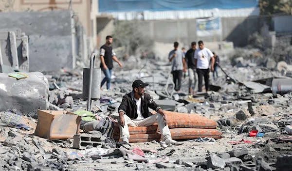 Palestinians walk by the buildings destroyed in the Israeli bombardment on al-Zahra, on the outskirts of Gaza City, Friday, Oct. 20, 2023. (AP)