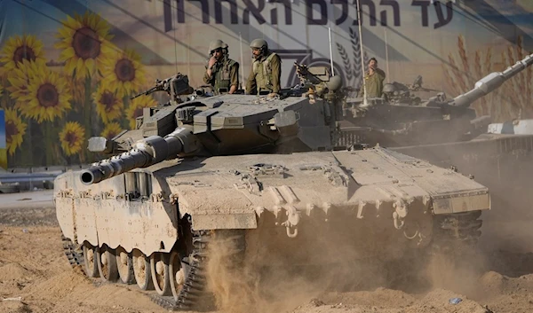 Israeli soldiers move a tank at a staging area near the border with Gaza Strip, in southern Palestine on Sunday, Oct. 15, 2023. (AP Photo/Ohad Zwigenberg)