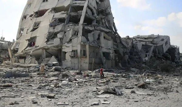 A Palestinian boy walks by buildings destroyed in the Israeli bombardment on al-Zahra on the outskirts of Gaza City on October 20, 2023 (AP)