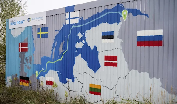 A sign reading ‘Nord Stream 2 Committed. Reliable. Safe’ hangs above a painted map at the natural gas receiving station in the Lubmin industrial estate in Lubmin, Germany (AP)