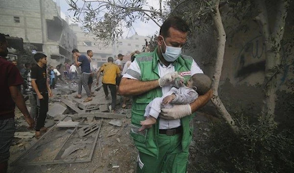 Palestinian medic takes a baby pulled out of buildings destroyed in the Israeli bombardment of the Gaza Strip in Rafah, Sunday, Oct. 22, 2023 (AP)