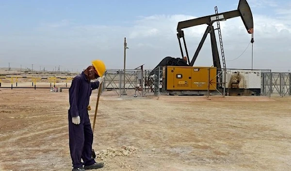 A worker stands across a pumpjack operating in the desert oil fields of Sakhir in southern Bahrain. (AFP)