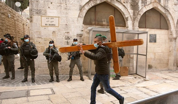 Christian man carries a cross along the Via Dolorosa ahead of the Good Friday procession in Jerusalem's Old City, on April 2, 2021. (AP)