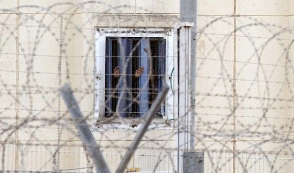 Palestinian prisoners can be seen through barbed wires from an Israeli occupation prison in November 2018. (AFP)