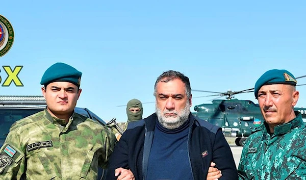 In this photo released by Azerbaijan's border guard service on Wednesday, Sept. 27, 2023, Azerbaijan's border guard officers pose with detained Ruben Vardanyan, center, in Nagorno-Karabakh. (via AP)