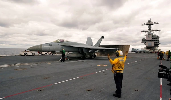 A catapult officer directs an F/A-18 E during flight training ops aboard the nuclear powered aircraft carrier USS Gerald R. Ford Thursday, Oct. 6, 2022, off the Virginia Coast (AP Photo/Steve Helber)