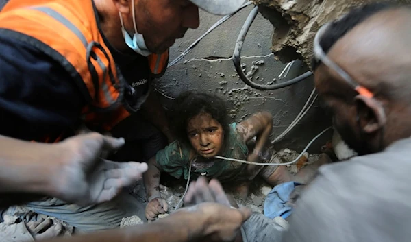 Palestinians try to pull a girl out of the rubble of a building that was destroyed by Israeli airstrikes in Jabaliya refugee camp, northern Gaza Strip, Wednesday, Nov. 1, 2023. (AP Photo/Abed Khaled)