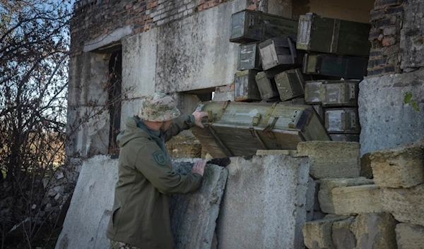 A sapper examines ammunition left by the Russian troops in the village of Kiseliovka close to Kherson, Ukraine, Friday, Nov. 10, 2023.(AP Photo/Efrem Lukatsky)