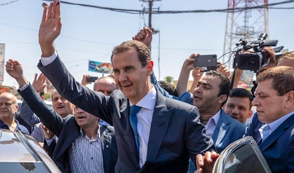 Syrian President Bashar Assad, waves to his supporters at a polling station during the Presidential elections in the town of Douma, in the eastern Ghouta region, near the Syrian capital Damascus, Syria, May 26, 2021. (AP)