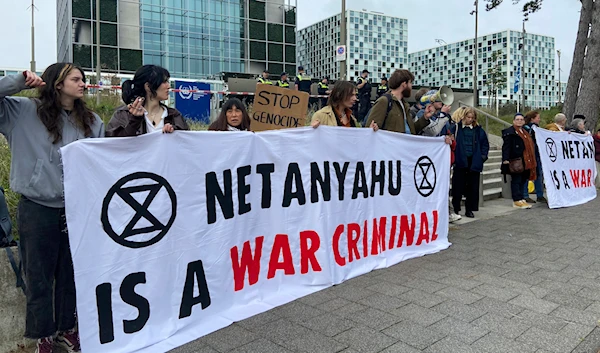 Activists hold up a banner denouncing Israeli Prime Minister Benjamin Netanyahu for Israel’s actions at the entrance of the International Criminal Court in The Hague on Oct. 23, 2023. (AP)