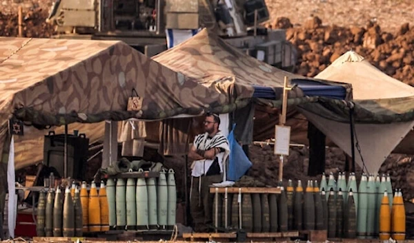 An IOF soldier stands next to artillery shells at a position near the Gaza Strip in southern occupied territories on November 1, 2023 (AFP)