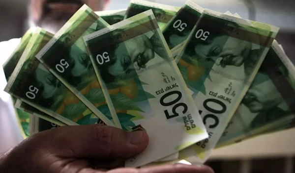 An undated photo of a man holding shekels (AFP)