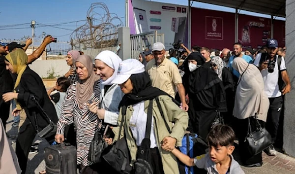 Palestinians with dual citizenship walk through a gate to enter the Rafah border crossing to Egypt in the southern Gaza Strip on November 1, 2023 (AFP)