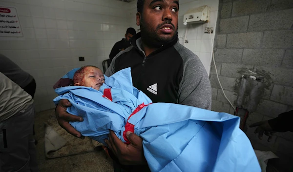 Palestinian relative carries the body of child Fawze Musleh, killed in the Israeli bombardment of the Gaza Strip at the morgue of al Aqsa Hospital in Deir al Balah, Gaza Strip, Sunday, Nov. 19, 2023. (AP)