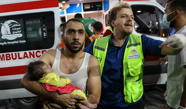 A man brings an injured baby into Al-Shifa Hospital in Gaza following an Israeli airstrike on October 12. (AFP via Getty Images)