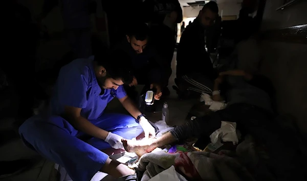 Palestinian medics treat a wounded person using torchlights after running out of power at the Indonesian hospital in Beit Lahiya during the ongoing bombardment of the northern Gaza Strip, Sunday, Nov. 19, 2023 (AP)