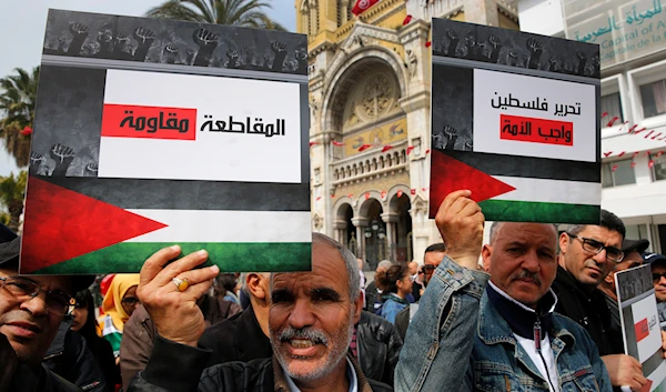 Tunisian protesters hold placards showing the Palestinian flag and Arabic that reads, "The boycott is resistance, and Liberating Palestine is the duty on the nation," March 31, 2019 (AP)