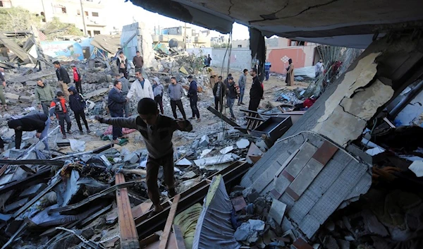 Palestinians stand by a building destroyed in Israeli bombardment overnight in Rafah, Gaza Strip, Friday, Nov. 24, 2023 (AP)