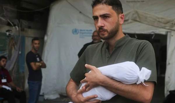 A grieving father carries the body of his own baby who was killed after an Israeli airstrike bombed the Gaza Strip on October 25. (AP)