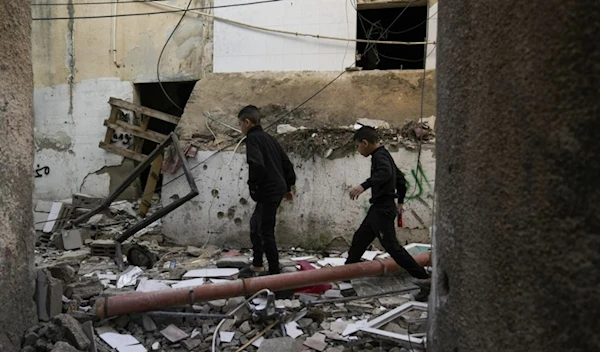 Palestinians walk by a damaged building following an Israeli deadly raid in Jenin refugee camp on November 26.   (AP)