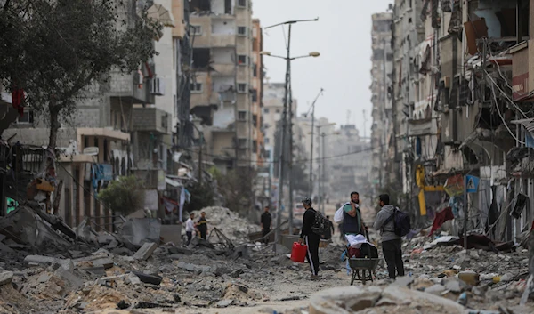 Palestinians walk through destruction in Shati refugee camp on Saturday, Nov. 25, 2023. on the second day of the temporary ceasefire between Hamas and Israel. (AP)