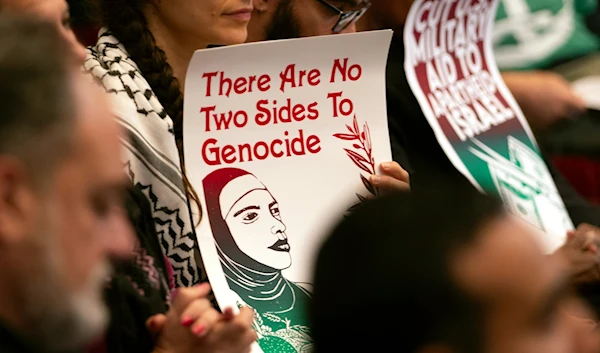 Audience members hold signs expressing their opinions on a resolution calling for an immediate cease-fire in Gaza, Monday, Nov. 27, 2023, in Oakland, California (AP)