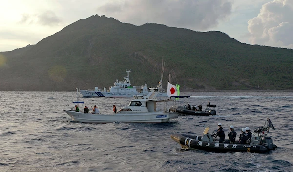 a Japanese Coast Guard boat and vessel sail alongside Japanese activists' fishing boat, not in photo, warning the activists away from a group of disputed islands called Senkaku by Japan and Diaoyu by China on Aug. 18, 2013 (AP)