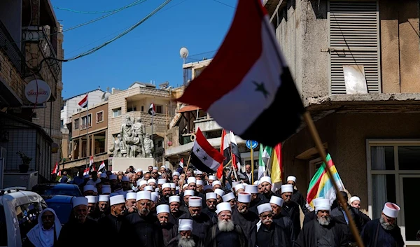 Druze men carry Syrian and Druze flags during a rally marking Syria's Independence Day, in the Druze village of Majdal Shamsin the Israeli-controlled Golan Heights Syria, Monday, April 17, 2023 (AP)